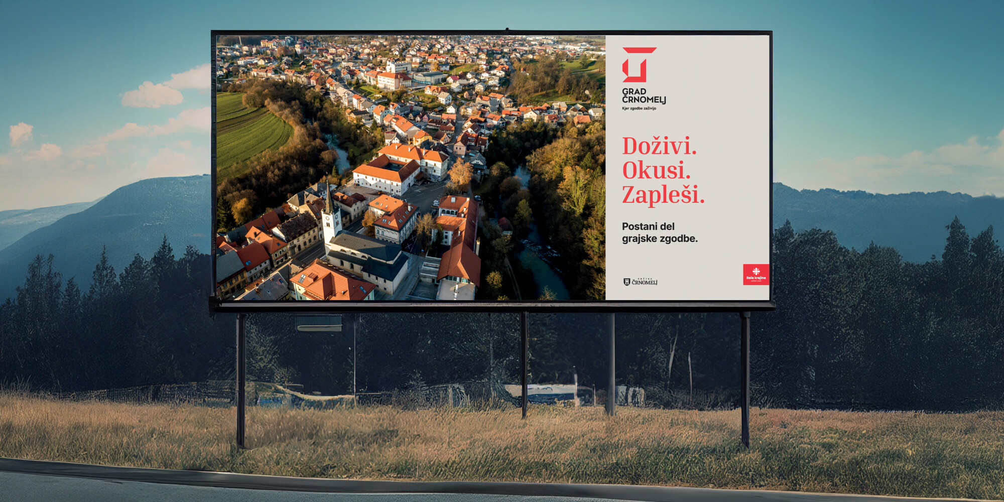 Zunanji velik plakat za Grad Črnomelj. Na sliki na vidno mesto in grad s ptičje perspektive. Napis na plakatu: »Doživi. Okusi. Zapleši. Postani del grajske zgodbe.«