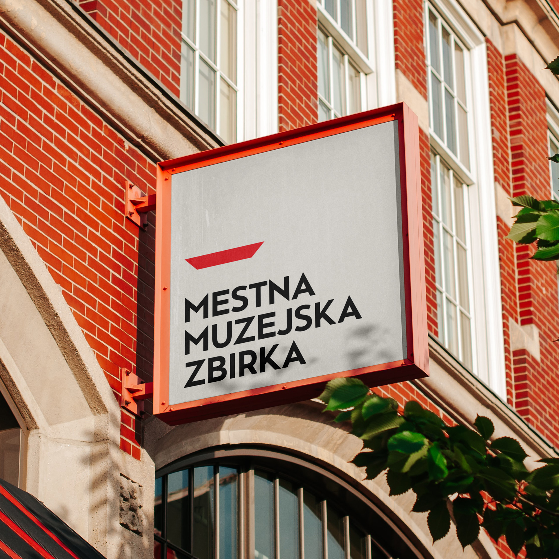 Tabla kvadratne oblike na fasadi stavbe. Na njej je napis: »Mestna muzejska zbirka«
