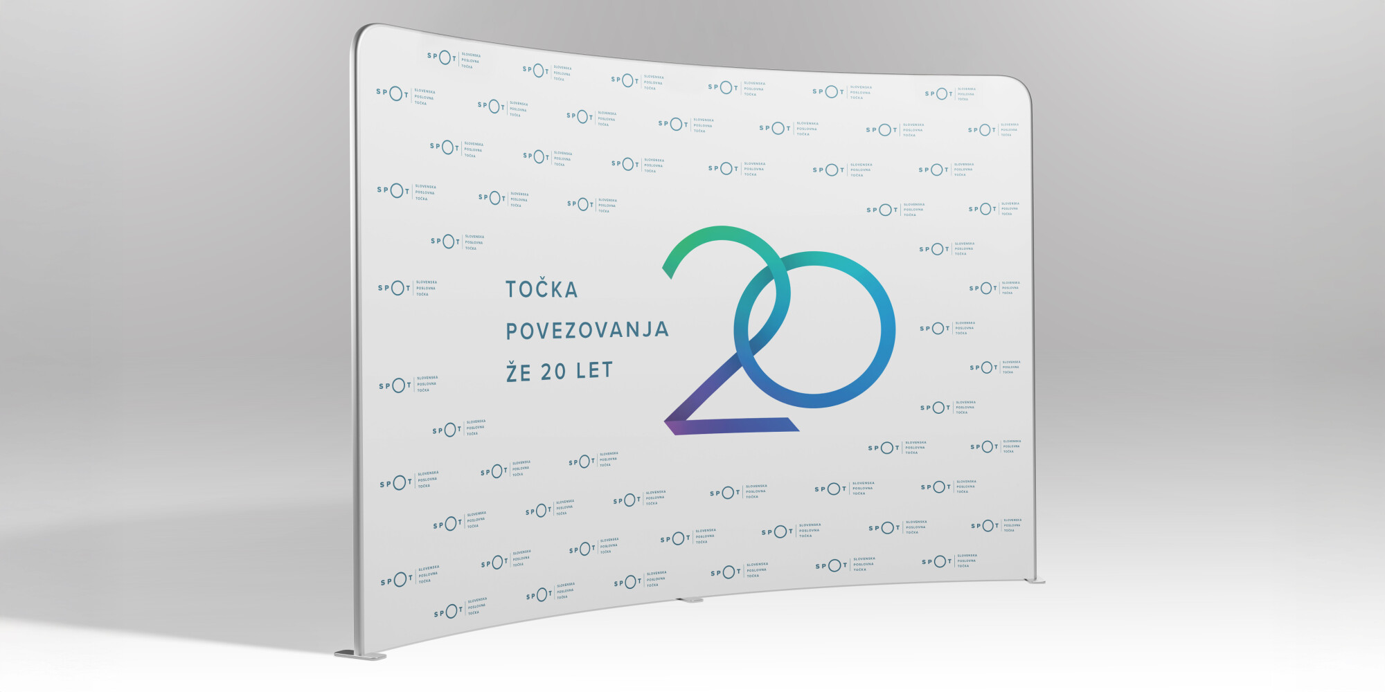Pano oziroma ozadje za fotografiranje na dogodku. Na beli podlagi je velika številka 20 in napis: »TOČKA POVEZOVANJA ŽE 20 LET« ter po vsej površini razporejeni logotipi SPOT. 