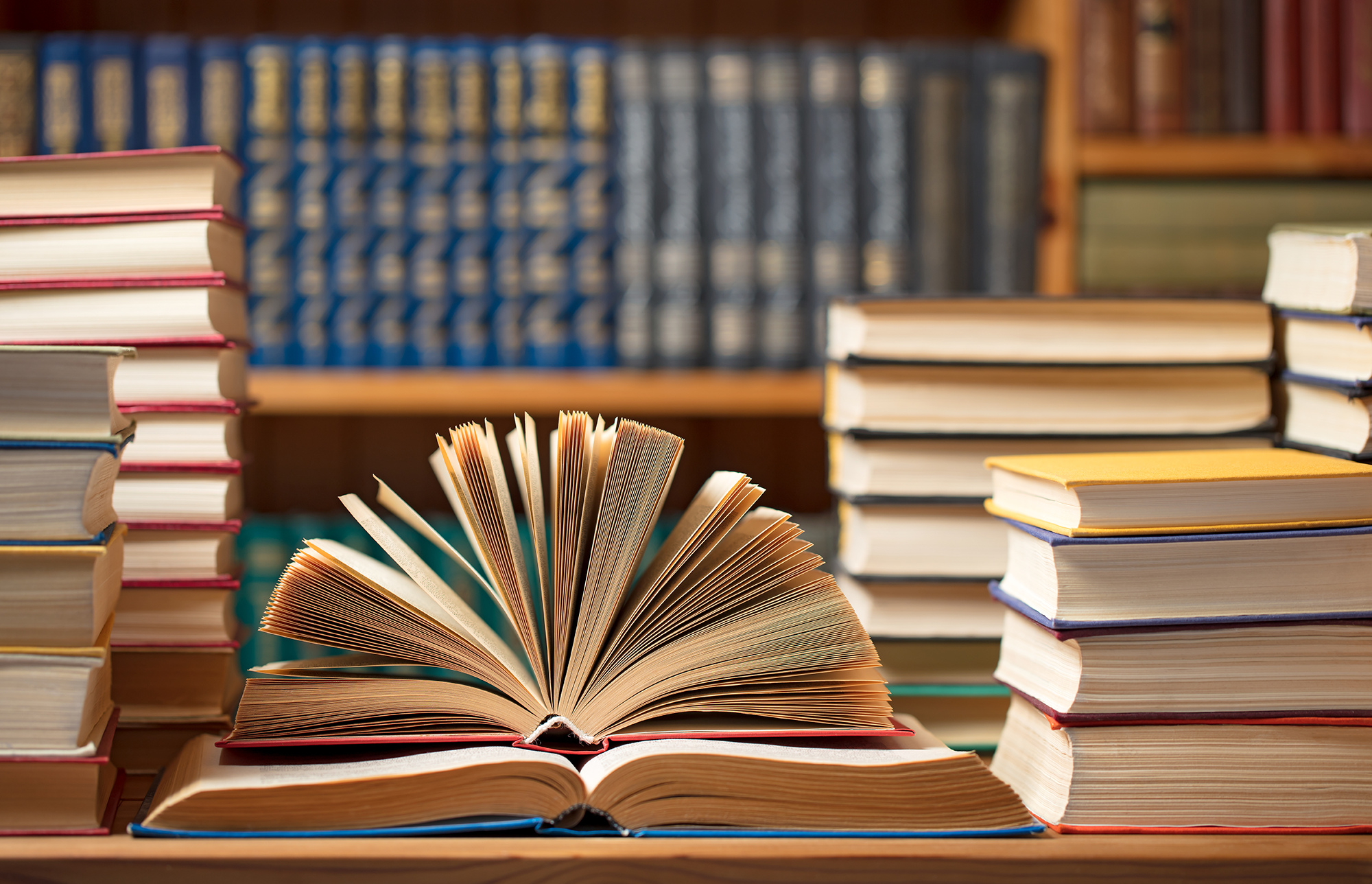 Knjižnica z odprtimi knjigami na mizi.