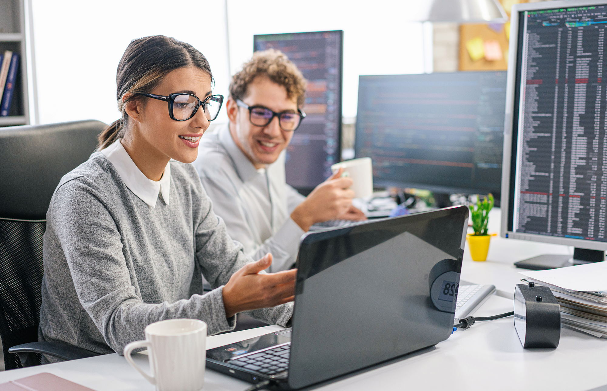 Sodelavca razpravljata v pisarni pred odprtimi prenosniki.